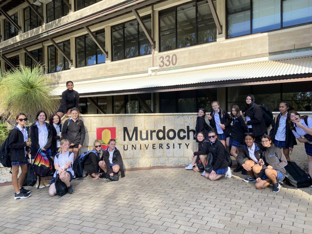 18 (female) CLC students standing in front of a Murdoch University Sign